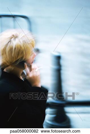 Woman holding cell phone in street, blurred View Large Photo Image Stock Image - Woman holding cell phone in street, blurred. Fotosearch