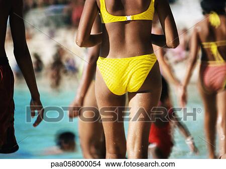 Picture - Woman wearing bikini on crowded beach, rear view, mid section. Fotosearch