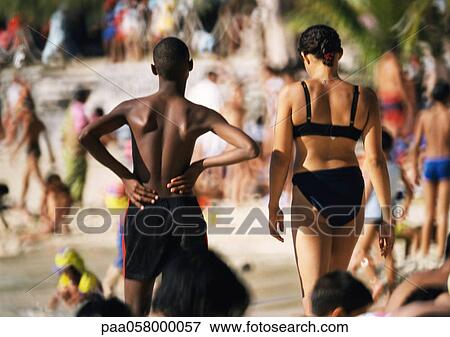 Young man and woman side by side on crowded beach, rear view View Large Photo Image Stock Photo - Young man and woman side by side on crowded beach, rear view. Fotosearch