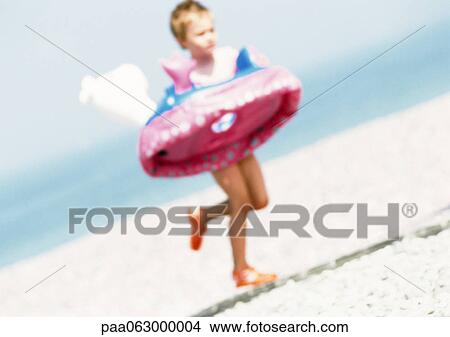 Child running with inner tube on beach, blurred View Large Photo Image Picture - Child running with inner tube on beach, blurred. Fotosearch