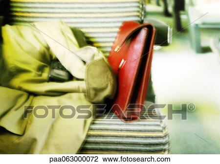 Stock Image - Coat and purse on seat, blurred. Fotosearch