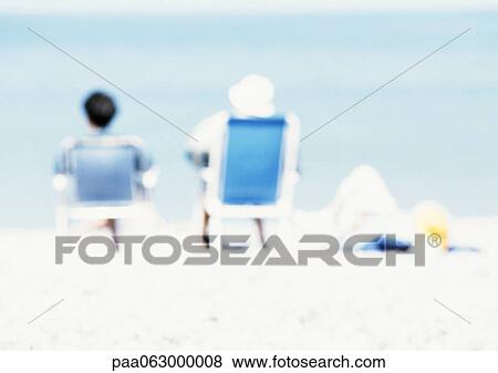 Couple sitting in chairs on the beach, rear view, blurred View Large Photo Image Stock Photo - Couple sitting in chairs on the beach, rear view, blurred. Fotosearch