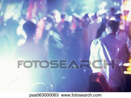 Stock Image - Crowd of people in night club, dancing, blurred. Fotosearch