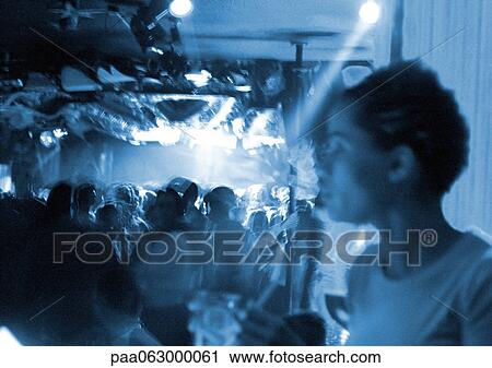 Stock Image - Crowd of people in nightclub, black and white, blurred.. Fotosearch