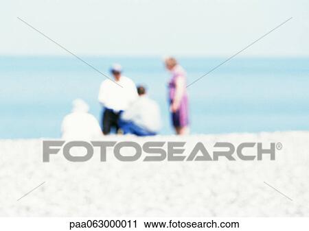 Stock Image - Group of people on beach, blurred. Fotosearch