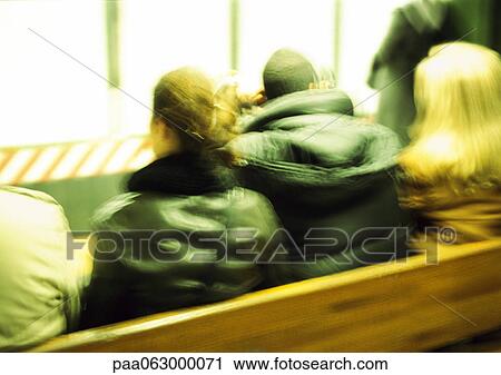 Stock Image - People in coats sitting on bench, rear view, close up. Fotosearch