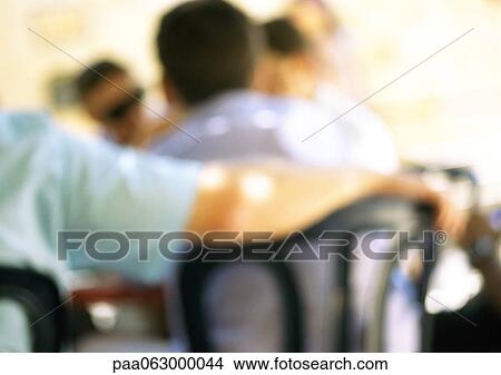 People sitting in restaurant, one person resting arm on back of other's chair, blurred View Large Photo Image Picture - People sitting in restaurant, one person resting arm on back of other's chair, blurred. Fotosearch