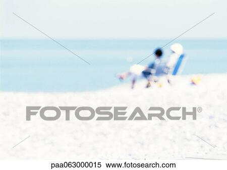 Stock Photography - People sitting on chairs on the beach, blurred. Fotosearch