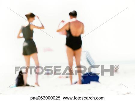 Stock Photography - People standing on the beach, rear view, blurred. Fotosearch