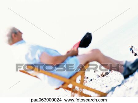 Picture - Person sitting in beach chair, blurred. Fotosearch
