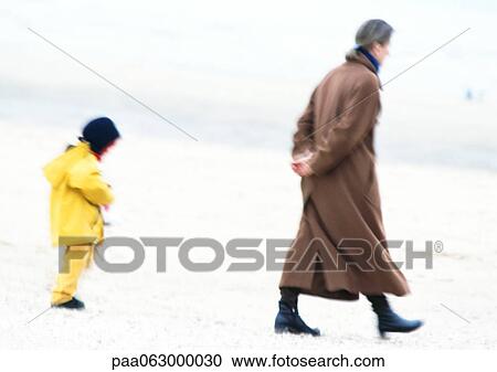 Woman and child in coats walking on beach, blurred View Large Photo Image Stock Image - Woman and child in coats walking on beach, blurred. Fotosearch