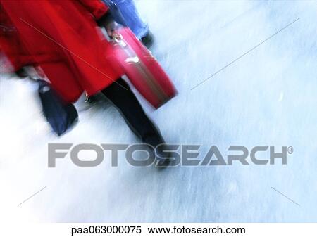 Stock Photography - Woman walking and carrying suitcase, lower section, blurred.. Fotosearch