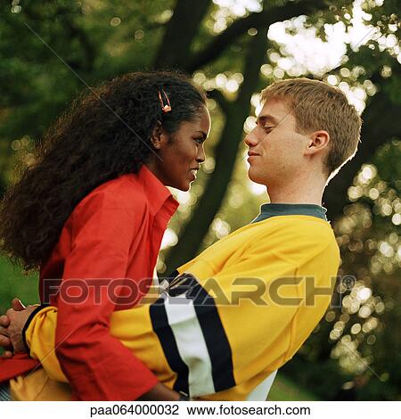 Stock Image - Young couple embracing outside, close-up. Fotosearch