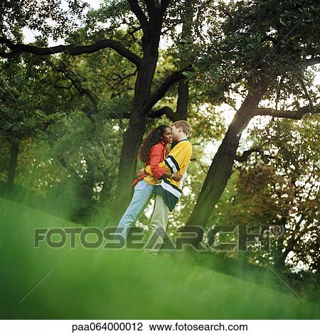 Young man and woman standing on grass, embracing, side view, full length View Large Photo Image Stock Image - Young man and woman standing on grass, embracing, side view, full length. Fotosearch