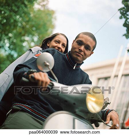 Young man and young woman on motor scooter, waist up, tilt View Large Photo Image Stock Photo - Young man and young woman on motor scooter, waist up, tilt. Fotosearch