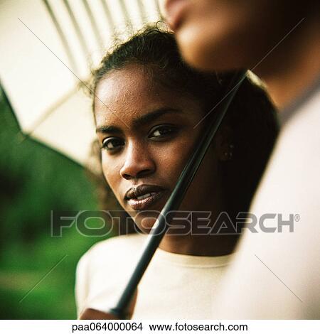 Picture - Young man and young woman underneath umbrella outside, close up.. Fotosearch