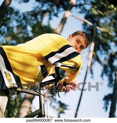 Young man leaning on handle bars of bicycle outside. View Large Photo Image Stock Photo - Young man leaning on handle bars of bicycle outside.. Fotosearch