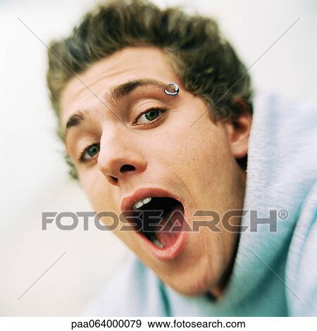Stock Photo - Young man looking at camera wtih mouth open, close-up, portrait.. Fotosearch