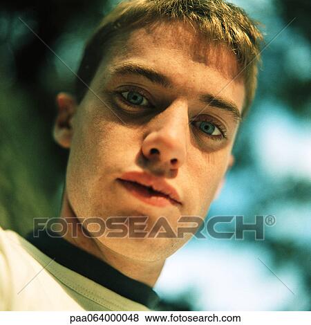 Stock Photo - Young man outside, looking at camera, close up, portrait, low angle view. Fotosearch