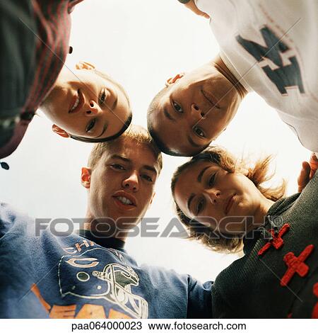 Stock Image - Young people huddling, head to head, view from below, close-up. Fotosearch