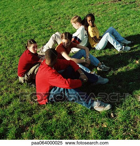 Stock Photography - Young people sitting on grass, high angle view. Fotosearch