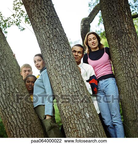 Stock Image - Young people standing between trees. Fotosearch
