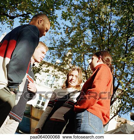 Young people talking together outside, low angle view View Large Photo Image Stock Photo - Young people talking together outside, low angle view. Fotosearch