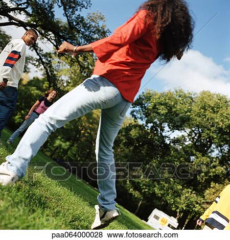 Young people together outside, young woman jumping in foreground, rear view View Large Photo Image Stock Photo - Young people together outside, young woman jumping in foreground, rear view. Fotosearch