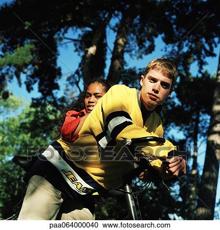 Stock Image - Young woman and young man on bike outside.. Fotosearch