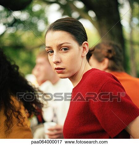 Young woman looking at camera, people in background. View Large Photo Image Stock Photo - Young woman looking at camera, people in background.. Fotosearch