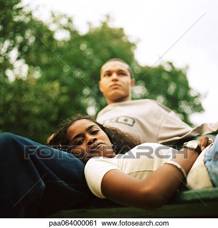 Stock Image - Young woman resting head on young man's lap, low angle view. Fotosearch