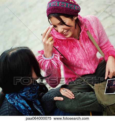 Stock Photography - Young women sitting together, smiling.. Fotosearch