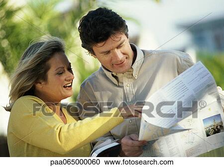 Stock Image - Man and woman looking at map, outside. Fotosearch
