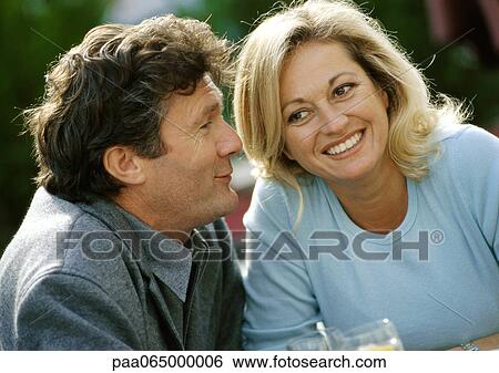 Stock Photograph - Man and woman sitting close together, smiling, close up.. Fotosearch