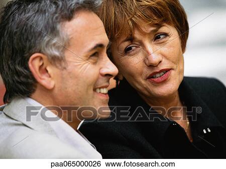 Stock Photograph - Man and woman sitting close together, woman talking to man, close up.. Fotosearch