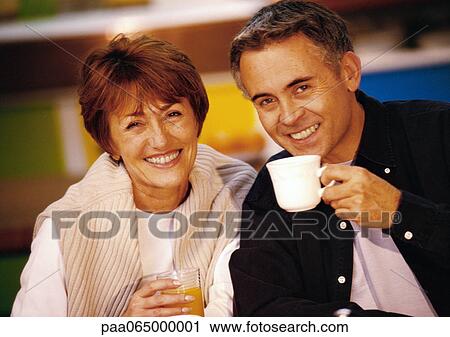 Man and woman sitting together smiling, man holding mug, close up. View Large Photo Image Stock Image - Man and woman sitting together smiling, man holding mug, close up.. Fotosearch