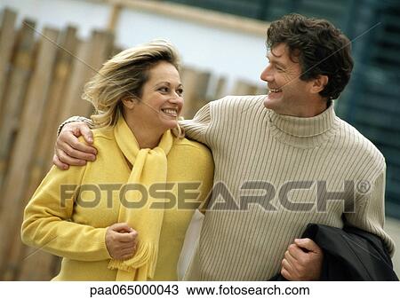 Man and woman smiling at each other, man's arm around woman, waist up View Large Photo Image Stock Image - Man and woman smiling at each other, man's arm around woman, waist up. Fotosearch