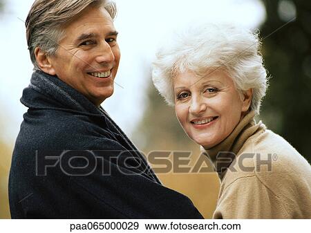 Stock Photo - Man and woman smiling over shoulders into camera, close-up. Fotosearch