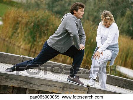 Man and woman stretching legs together on wooden walkway View Large Photo Image Stock Photography - Man and woman stretching legs together on wooden walkway. Fotosearch
