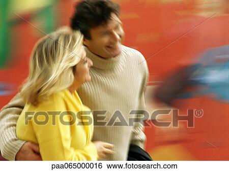 Stock Photograph - Man and woman walking together, man's arm around woman, blurred. Fotosearch