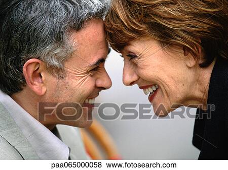 Stock Photo - Mature man and woman looking at each other touching foreheads smiling, close up.. Fotosearch