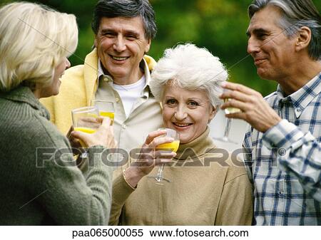 Stock Photography - Mature people standing together with drinks in hands, close up.. Fotosearch