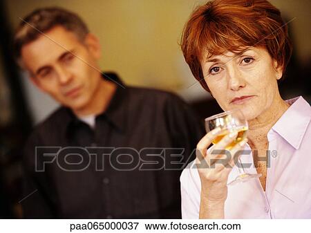 Woman holding glass, man blurred in background, head and shoulders, close-up. View Large Photo Image Stock Photo - Woman holding glass, man blurred in background, head and shoulders, close-up.. Fotosearch