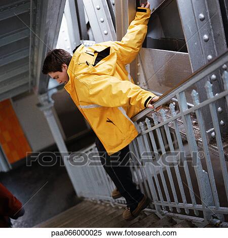Teenage boy in raincoat sliding down handrail in stairway View Large Photo Image Stock Photography - Teenage boy in raincoat sliding down handrail in stairway. Fotosearch