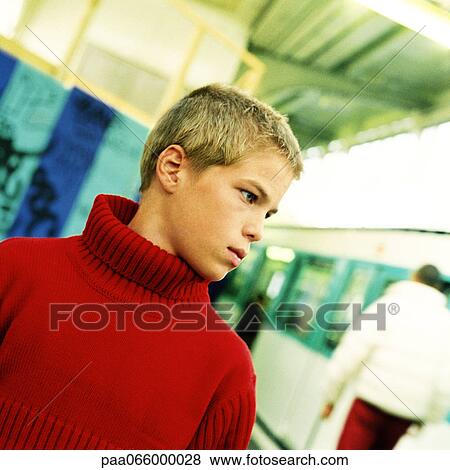 Stock Photo - Teenage boy standing, head and shoulders, with subway train in background. Fotosearch