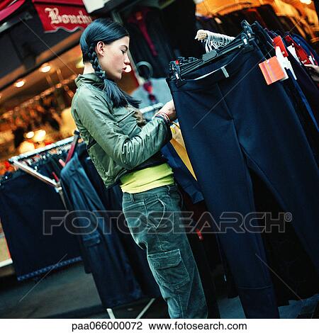 Teenage girl looking at racks of clothing, outside View Large Photo Image Stock Image - Teenage girl looking at racks of clothing, outside. Fotosearch