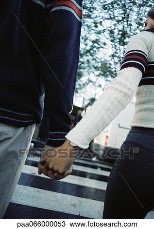 Young couple holding hands at pedestrian crossing, close up, rear view View Large Photo Image Stock Image - Young couple holding hands at pedestrian crossing, close up, rear view. Fotosearch