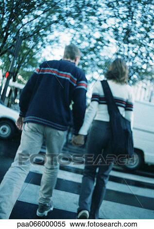 Young couple holding hands, crossing at pedestrian crossing, blurred, rear view View Large Photo Image Stock Photography - Young couple holding hands, crossing at pedestrian crossing, blurred, rear view. Fotosearch