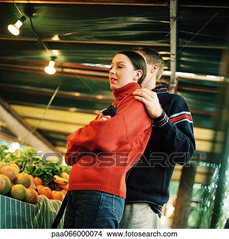 Young couple next to produce at market, low angle view View Large Photo Image Picture - Young couple next to produce at market, low angle view. Fotosearch