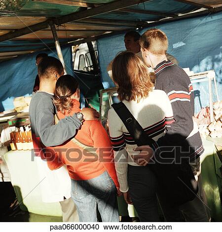 Young couples with arms around each other, standing in street market, rear view View Large Photo Image Stock Image - Young couples with arms around each other, standing in street market, rear view. Fotosearch